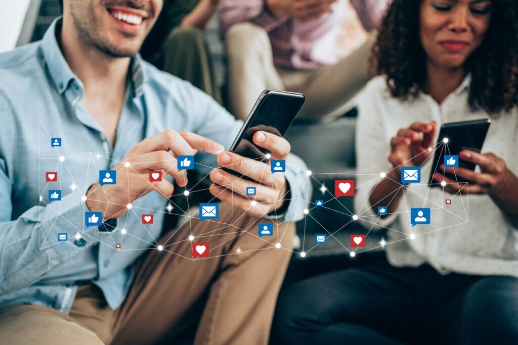 A group of young adults are sitting and looking at their smartphones. Social media icons hover over the image.